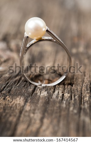 Jewelry ring with pearl on wood