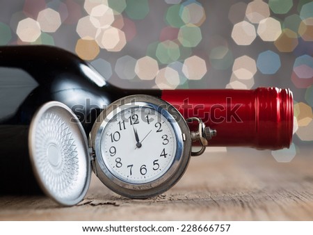 Clock and red wine against holiday lights