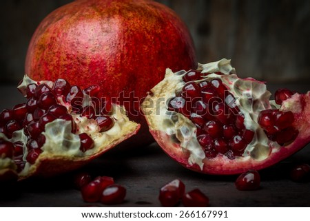 Some red juicy pomegranate, whole and broken, on black slate plate