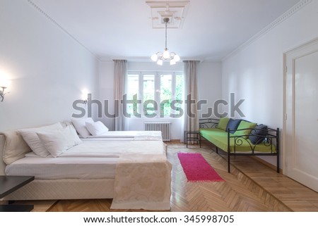 Interior of modern comfortable hotel room with double bed and green sofa