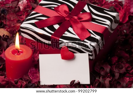 gift box with paper label and candle on rose petals