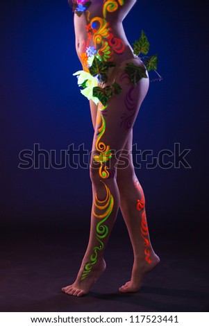 woman legs cover by glowing make-up and flowers
