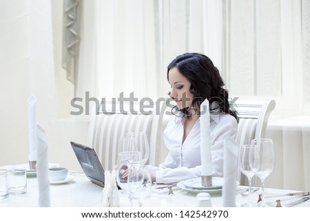 Lovely woman working at computer in restaurant