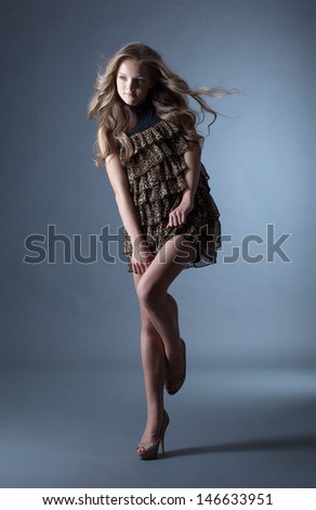 Young curly model posing in leopard print dress