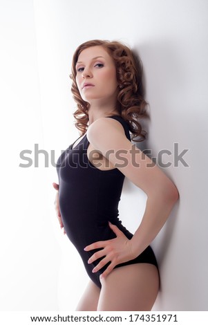 Cute slim brunette posing leaning against wall