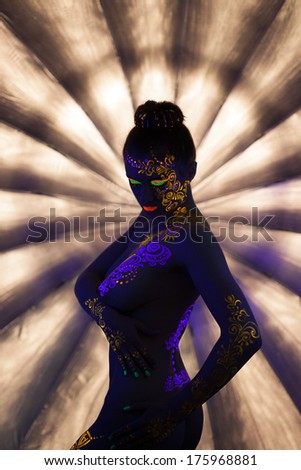 Sexy nude girl with glowing pattern under UV light