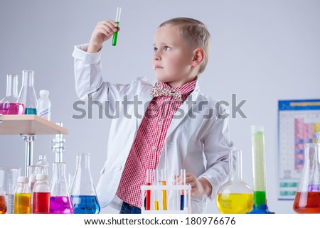 Cute boy looking at color of reagent in test-tube