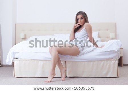 Image of curvy young girl sitting on hotel bed