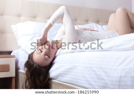 Sensual young woman lying on bed upside down
