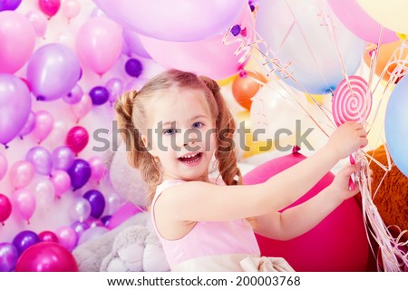Merry little girl posing with bunch of balloons