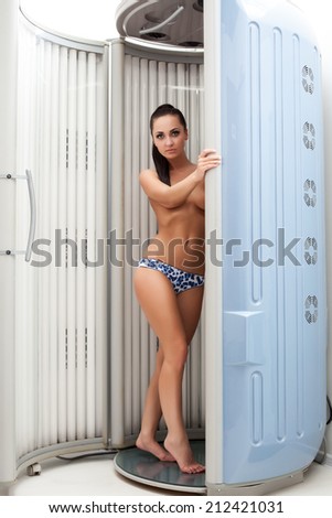 Pretty topless woman posing in tanning booths