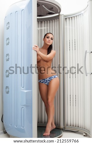 Sexy topless brunette posing in tanning booths