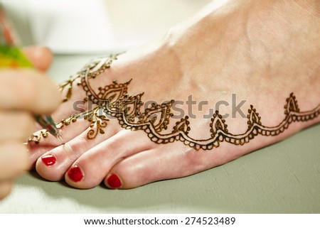Mehendi. Master applying henna on model\'s leg