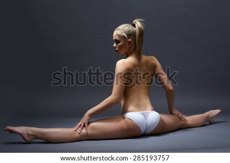 Rear view of topless girl doing gymnastic split