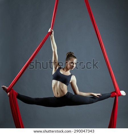 Cute dancer doing gymnastic split on aerial silks