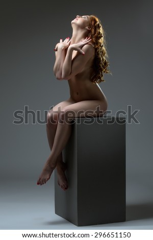 Seductive redhead woman sitting naked on cube