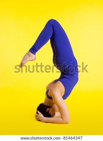 Girl in blue stand on head - yellow background