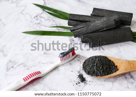 Toothpaste by activated charcoal powder on marble table