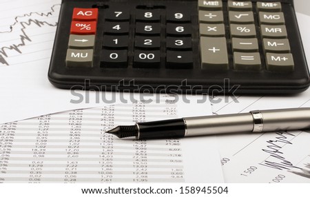 Business still-life of ink pen, charts, calculator, tables