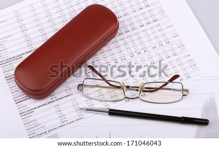 Business still-life of a black pen, charts, eyeglasses, case