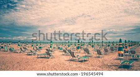 Retro color sand beach with deckchairs and umbrellas. Vintage color effect used.