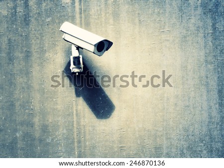 Grunge security camera with shadow on the public cement concrete wall background.