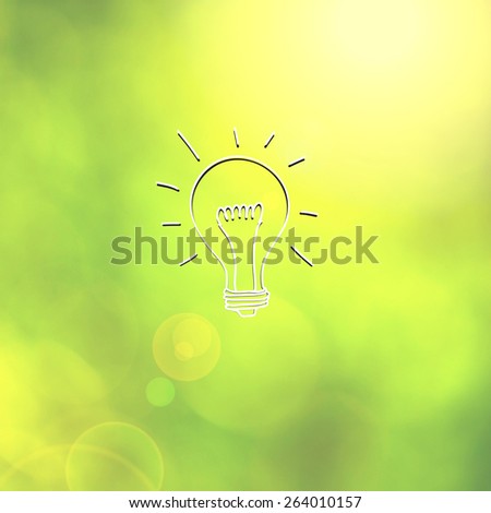 Hand drawing creative light bulb on blurred sunny nature background as concept. Abstract yellow green color blurry background.
