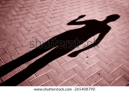 Marsala colored shadow of running female on soft red tiled city floor. Marsala color used.