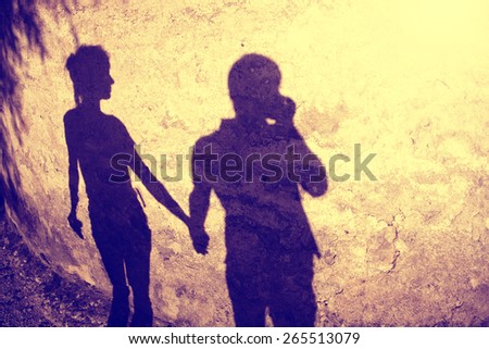 Vintage color silhouette of two people holding hands background, shadow of two adult (girl and boy) holding hands at Sunset light. Vintage color effect and grunge effect used.