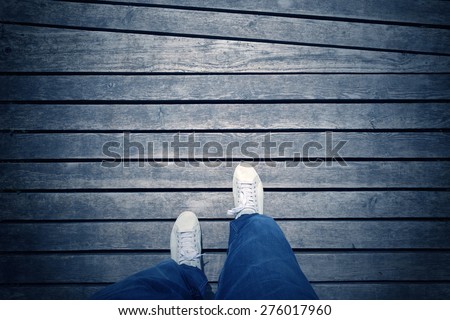 White foot on shoes from an aerial view on blue colored wooden background. Point of view man walking on aged blue color wooden floor.  Blue color filter effect and vignetting used.