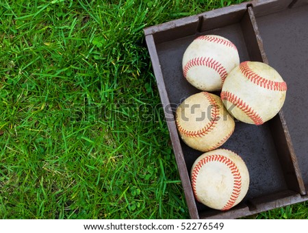 old baseballs in a wooden box on the field, copy space on grass at left