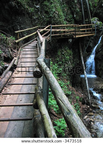 a wooden path leads through a gorge with waterfall