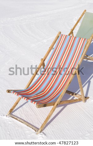 Two deck chairs in snow in winter time
