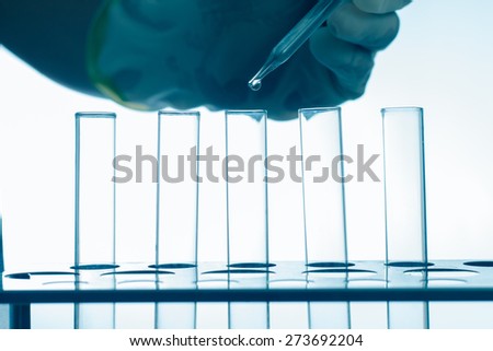 Pipette adding fluid in to test tubes,blue style background