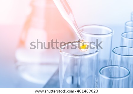 Laboratory pipette with drop of liquid over glass test tubes