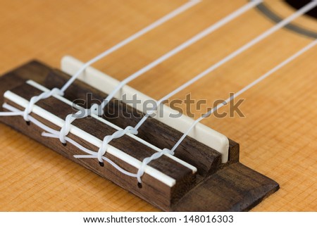 Closeup of ukulele hawaiian guitar body. Focus on bridge.