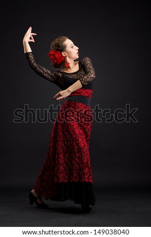 Flamenco dancer in white dress with red earrings over dark background