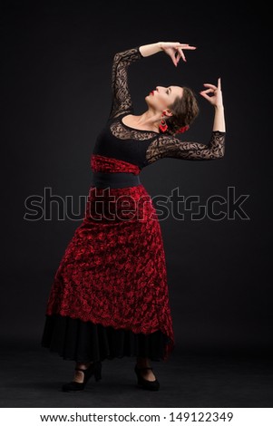 Flamenco dancer in white dress with red earrings over dark background