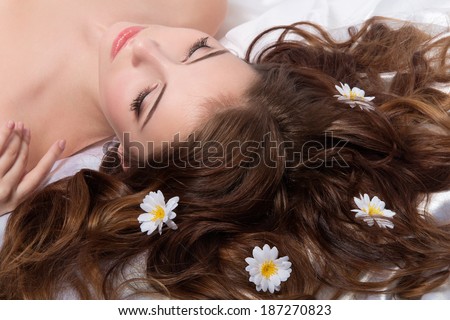 Portrait of young brunette woman with camomile flowers in her hair.Spa concept