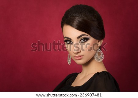 Portrait of young beautiful asian woman with evening make-up over dark red background