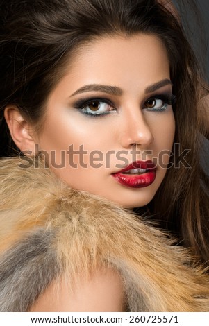Closeup portrait of young beautiful brunette woman with cherry lips wearing fur jacket