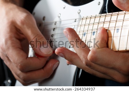 Hands of man playing electric guitar closeup. Bend technique.