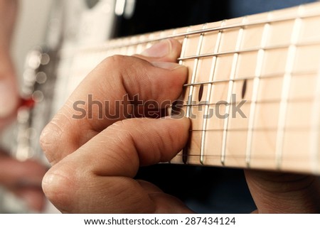 Close-up of man\'s hands playing electric guitar with red pick closeup