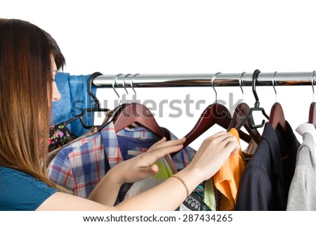 Beautiful young woman near rack with clothes choosing what to take. Nothing to wear, shopping and sale  concept