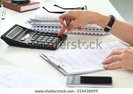 Close up of female accountant or banker making calculations. Savings, finances and economy concept