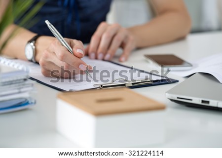 Close-up of female hands. Woman writing something  sitting at her office