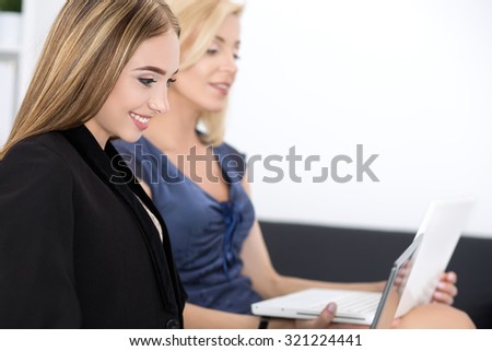 Two beautiful business women sitting at seminar and writing something. Business education and success concept