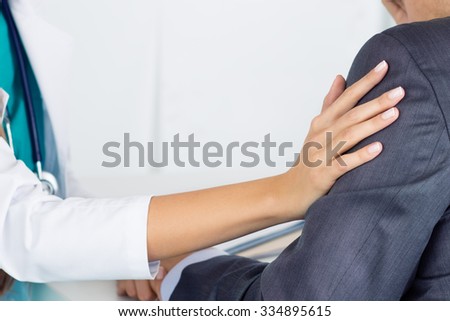 Close-up of friendly female medicine doctor\'s hand touching male patient\'s arm to support him. Bad news, stress and depression concept.