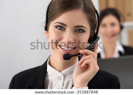 Portrait of call center worker accompanied by her team. Smiling customer support operator at work. Help and support concept