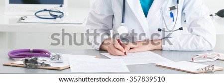 Female medical doctor writing something sitting at her office. Healthcare and medical concept.. Letter box format